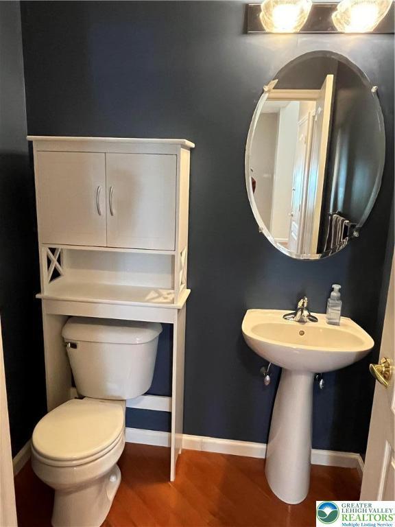 bathroom with baseboards, wood finished floors, and toilet