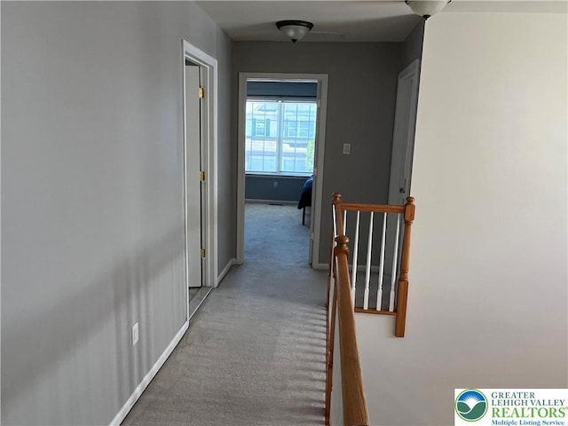 corridor featuring carpet floors, baseboards, and an upstairs landing