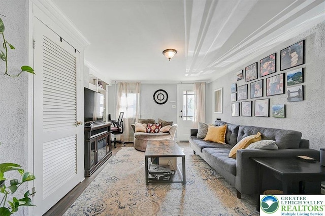 living room featuring ornamental molding, a textured wall, and wood finished floors