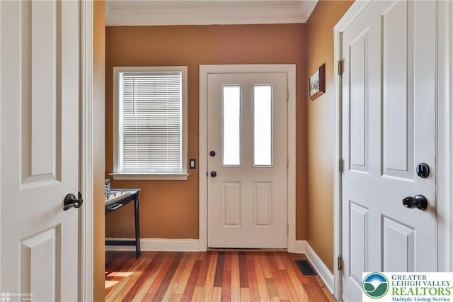 entryway featuring crown molding, light wood-style floors, baseboards, and visible vents
