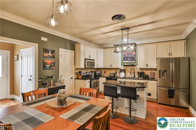 kitchen featuring crown molding, dark countertops, a sink, appliances with stainless steel finishes, and backsplash