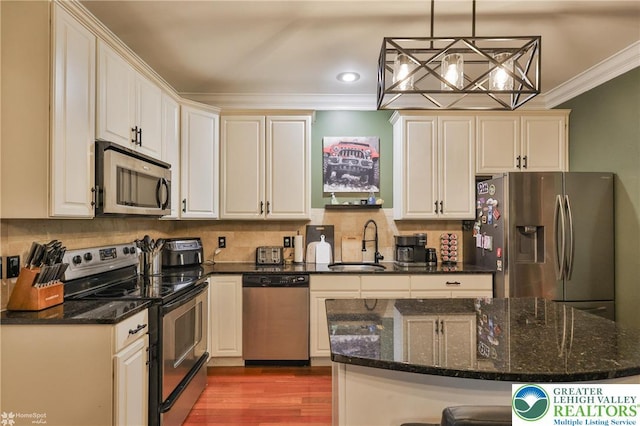 kitchen featuring backsplash, crown molding, appliances with stainless steel finishes, a sink, and recessed lighting