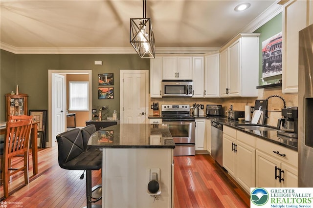 kitchen with a sink, a kitchen bar, hardwood / wood-style flooring, and stainless steel appliances