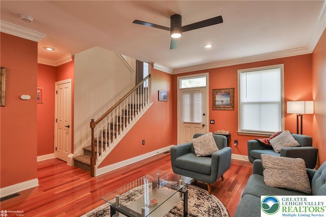 living room featuring baseboards, ornamental molding, stairs, and visible vents