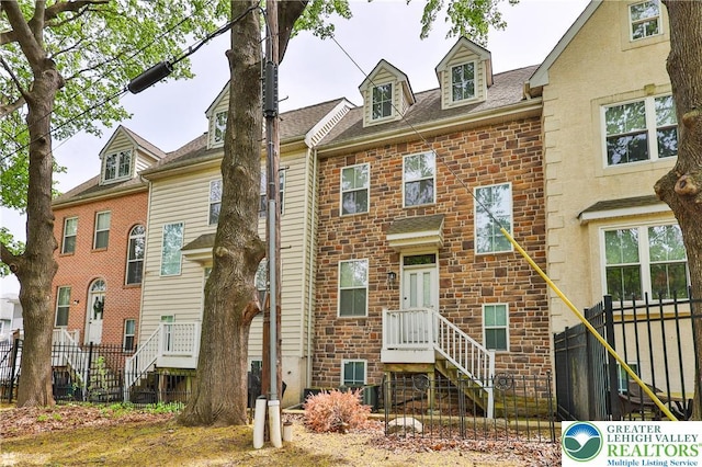 townhome / multi-family property with roof with shingles and fence