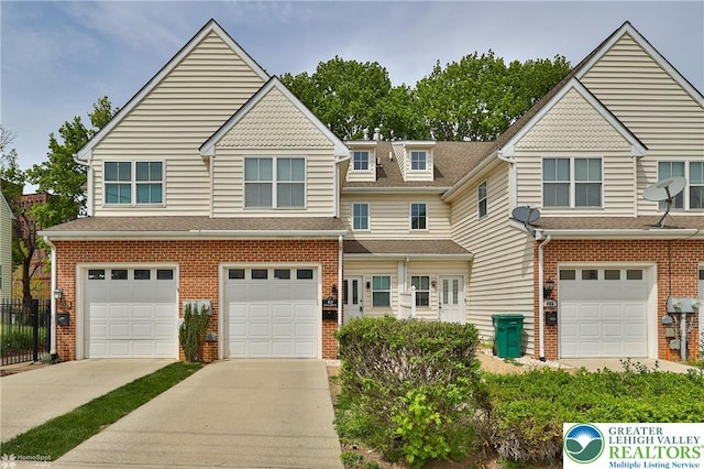 townhome / multi-family property with an attached garage, fence, driveway, and brick siding