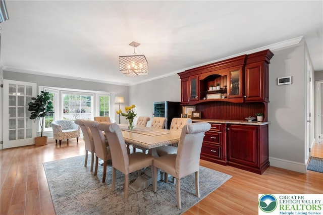 dining area featuring light wood-style floors, ornamental molding, baseboards, and an inviting chandelier