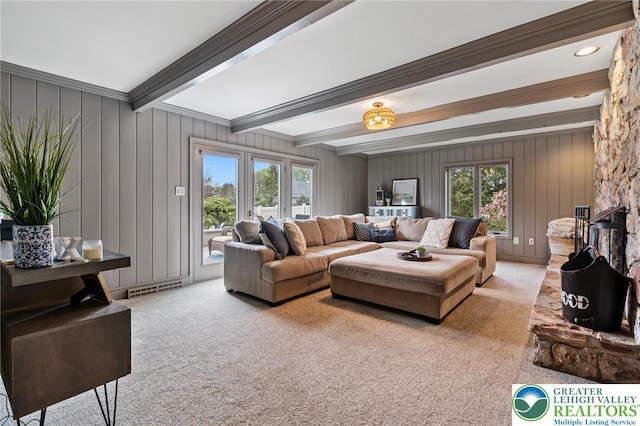 carpeted living area with visible vents and beam ceiling