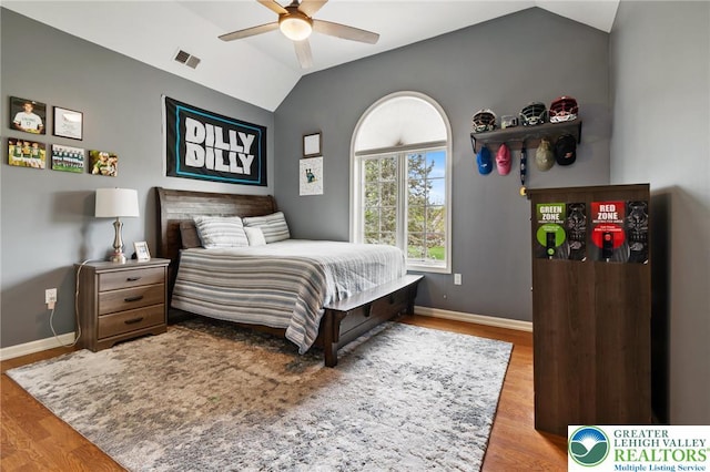 bedroom featuring baseboards, vaulted ceiling, wood finished floors, and visible vents