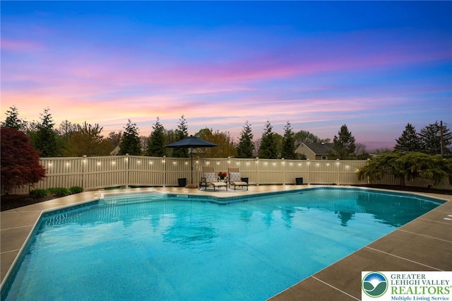 pool at dusk featuring a fenced in pool and fence