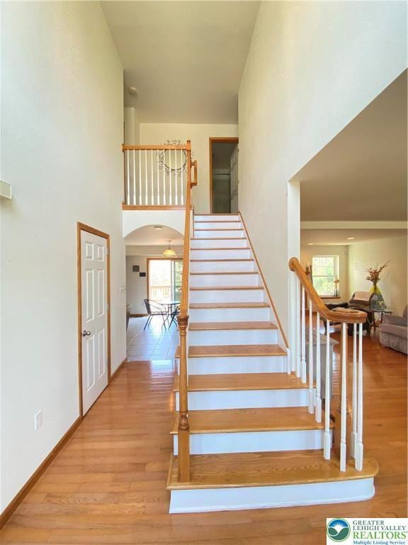 178 Stoney Ledge Dr, Jackson Twp, PA 18360 - stairway featuring baseboards, arched walkways, a towering ceiling, and wood finished floors