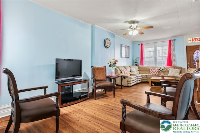 living area with crown molding, a ceiling fan, and wood finished floors
