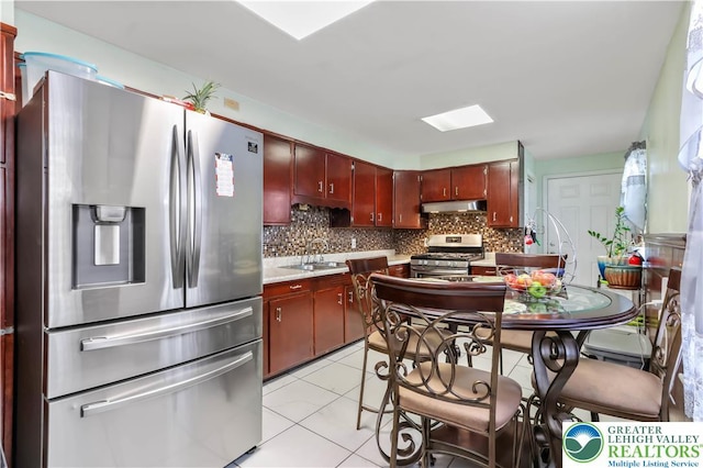 kitchen with under cabinet range hood, light countertops, appliances with stainless steel finishes, and tasteful backsplash