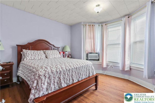bedroom featuring baseboards, wood finished floors, and cooling unit