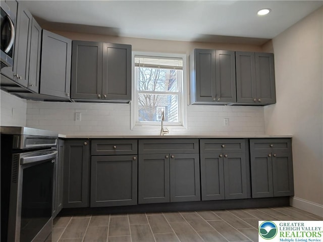 kitchen featuring a sink, gray cabinets, stainless steel appliances, recessed lighting, and decorative backsplash