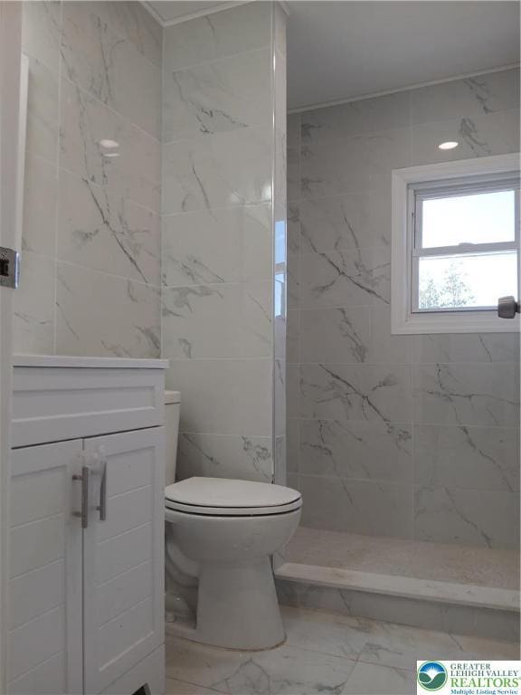 full bath with vanity, a tile shower, toilet, and marble finish floor
