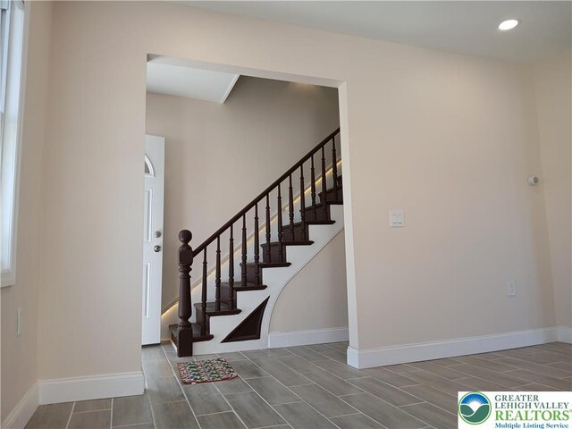 staircase with baseboards, wood finish floors, and recessed lighting