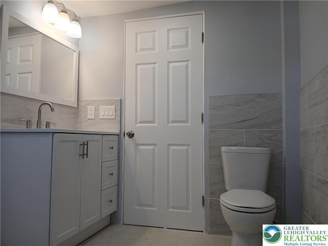 bathroom with vanity, toilet, and tile walls