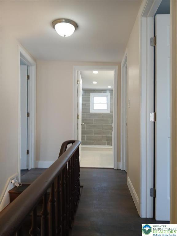 hall with baseboards and dark wood-style flooring