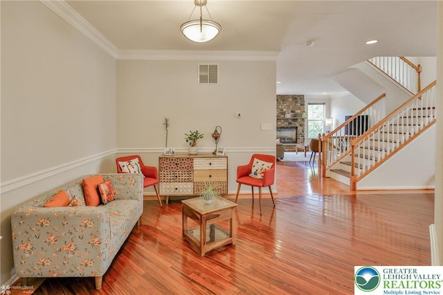 interior space featuring a stone fireplace, ornamental molding, visible vents, and stairway