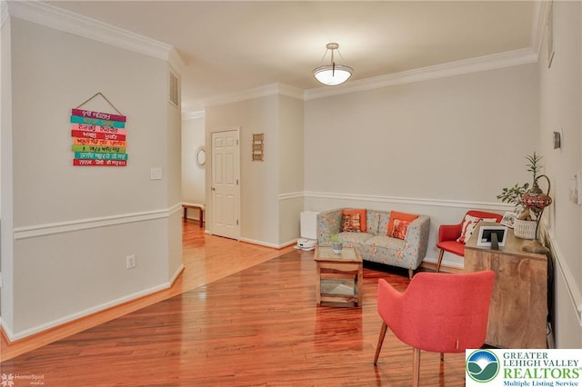 living area with crown molding, wood finished floors, and baseboards