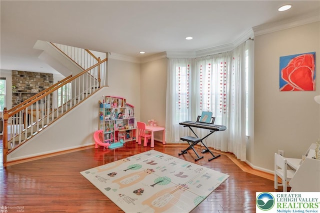 recreation room featuring wood finished floors, baseboards, ornamental molding, and recessed lighting