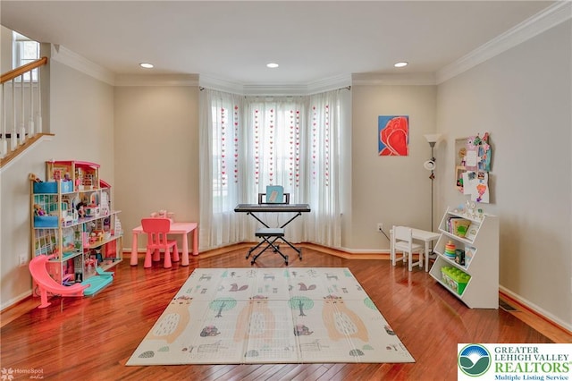 recreation room with crown molding, plenty of natural light, and wood finished floors