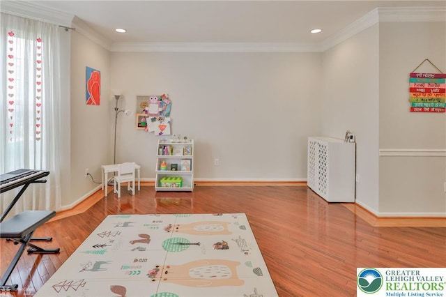 recreation room with wood finished floors, baseboards, ornamental molding, and recessed lighting