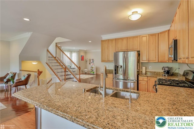kitchen featuring crown molding, stainless steel appliances, light stone countertops, and a sink