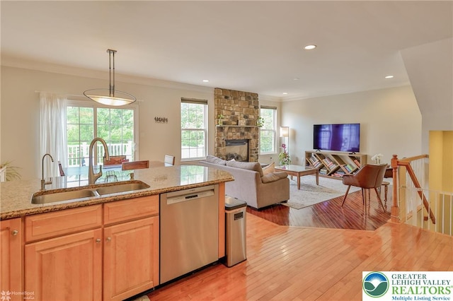 kitchen featuring a sink, light stone counters, dishwasher, light wood finished floors, and crown molding