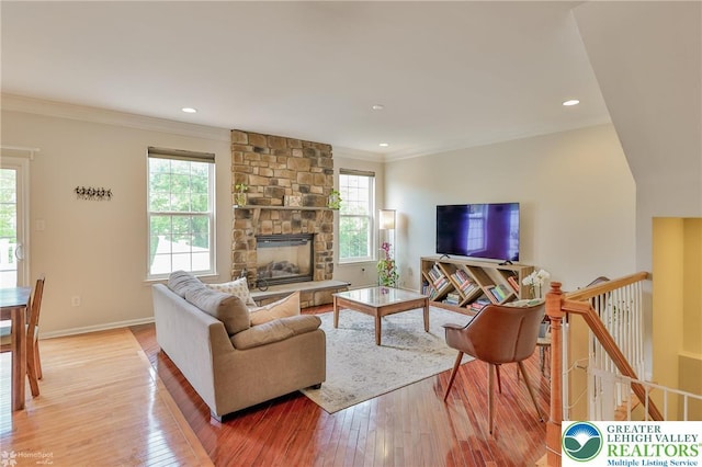 living area featuring recessed lighting, a fireplace, light wood finished floors, crown molding, and baseboards