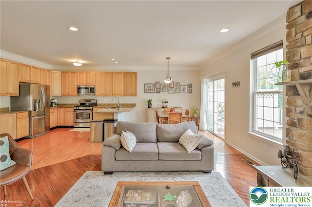 living area featuring crown molding, visible vents, baseboards, light wood-style floors, and recessed lighting
