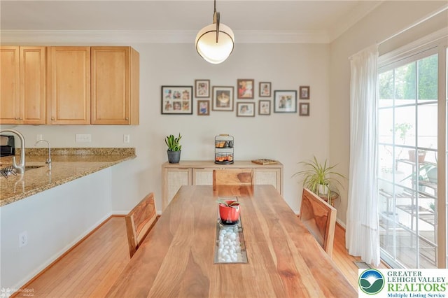 dining room with light wood-style flooring and crown molding