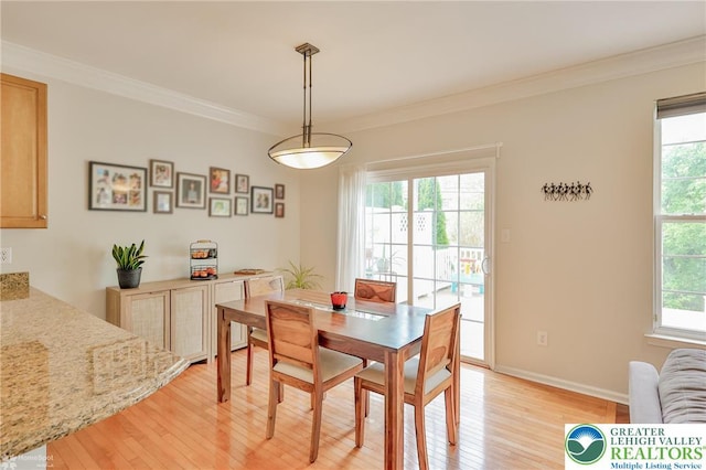 dining room with light wood finished floors, crown molding, and baseboards