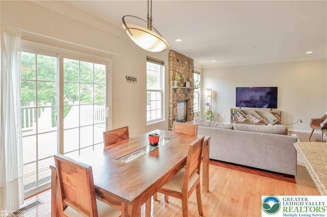 dining room featuring light wood-type flooring, visible vents, a stone fireplace, and recessed lighting