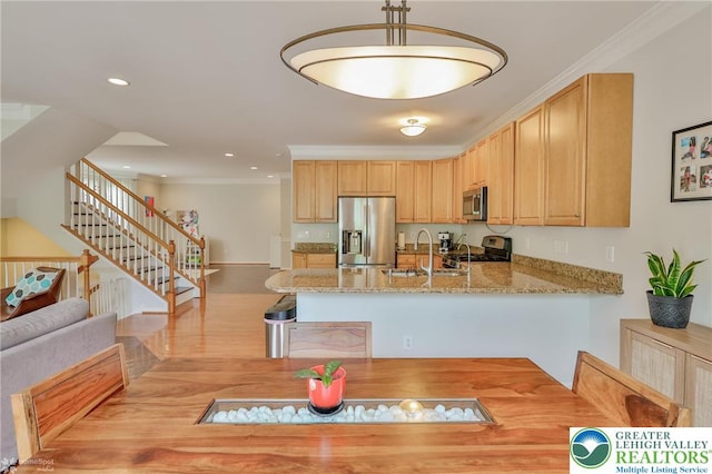 kitchen with a sink, a peninsula, stainless steel appliances, light wood finished floors, and light stone countertops