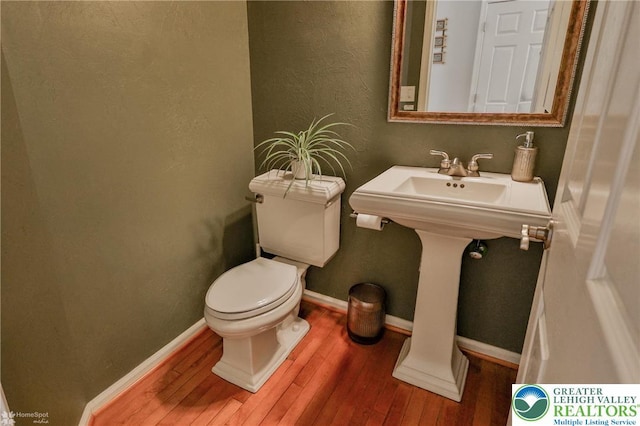 half bath featuring toilet, baseboards, and hardwood / wood-style floors