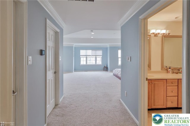 hall with crown molding, light carpet, and baseboards