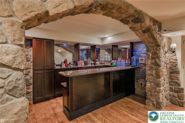 bar with light wood-style flooring and a dry bar