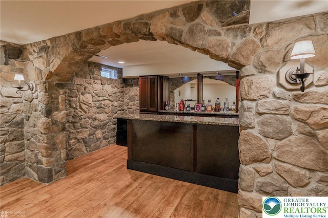 bar featuring light wood-style floors and a bar
