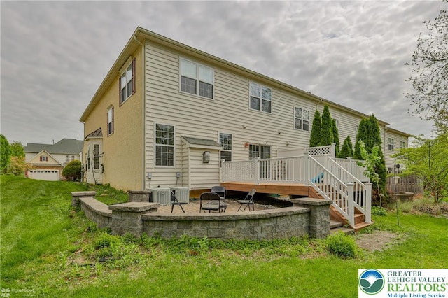 rear view of property featuring a lawn, a patio, a wooden deck, and a fire pit