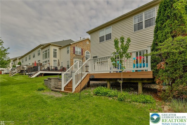 rear view of house featuring stairway, a wooden deck, and a yard