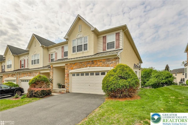 townhome / multi-family property featuring stone siding, a standing seam roof, an attached garage, and driveway