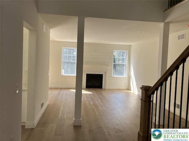 unfurnished living room with visible vents, baseboards, wood finished floors, and a fireplace