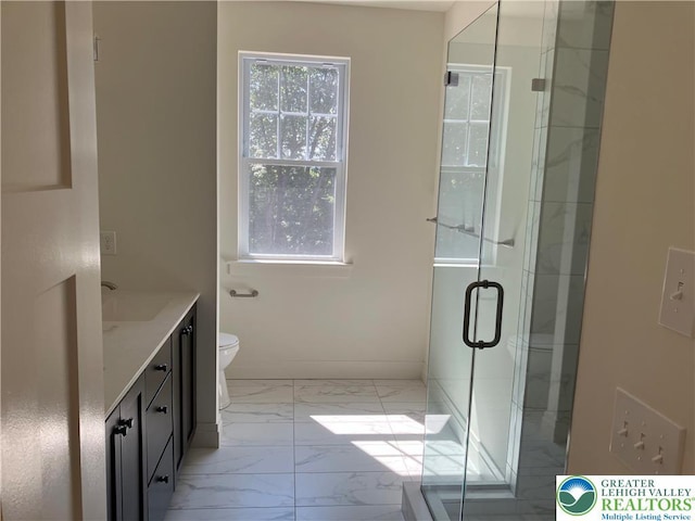 bathroom featuring vanity, toilet, marble finish floor, baseboards, and a shower stall
