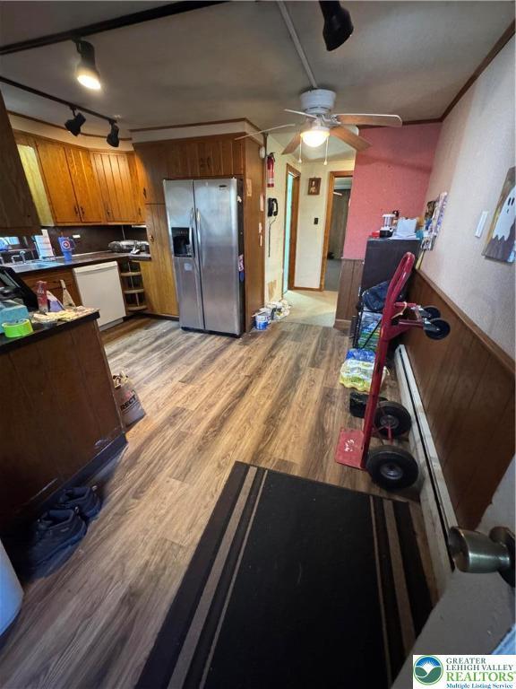 kitchen with brown cabinets, white dishwasher, ceiling fan, stainless steel fridge, and light wood-type flooring