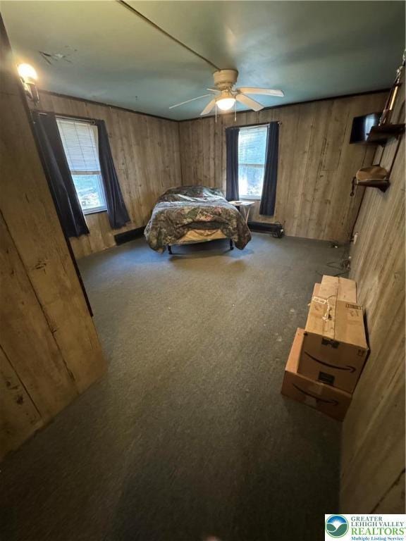 bedroom featuring carpet, a ceiling fan, and wood walls
