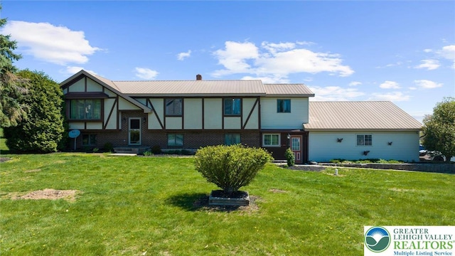 view of front of property featuring metal roof, a chimney, a front lawn, and brick siding