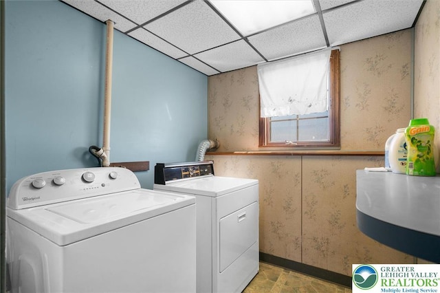 clothes washing area featuring separate washer and dryer, wallpapered walls, and baseboards