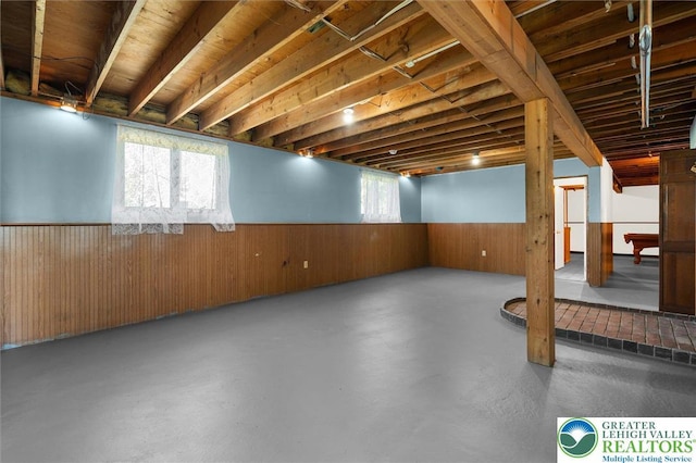 below grade area with wooden walls, plenty of natural light, and wainscoting